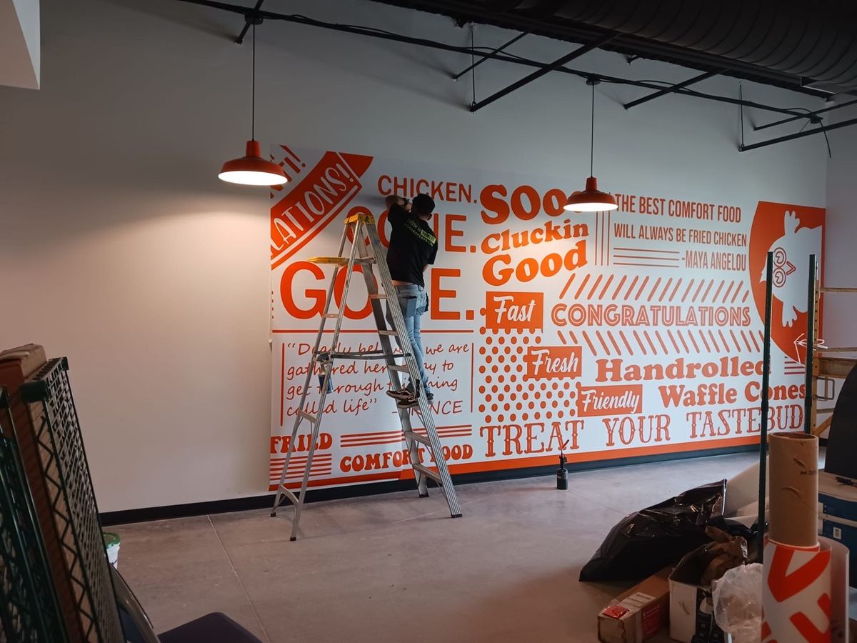 Instalación de wall wrap naranja con composición tipográfica