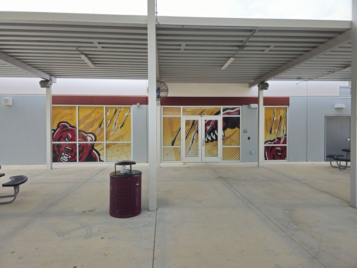 Fachada comercial con gráfica microperforada en puertas y ventanales